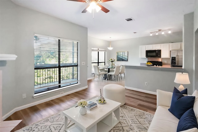 7340 Skillman St Unit 1109, Dallas, TX 75231 - living area with healthy amount of natural light, ceiling fan, wood finished floors, and baseboards