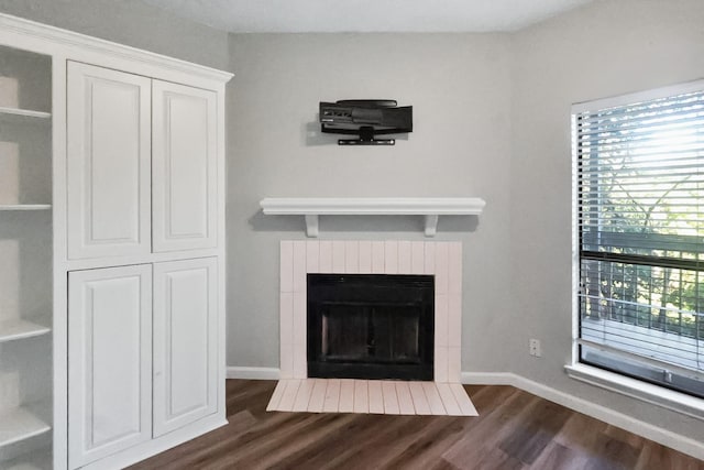 7340 Skillman St Unit 1109, Dallas, TX 75231 - unfurnished living room featuring dark wood finished floors, a fireplace with flush hearth, and baseboards