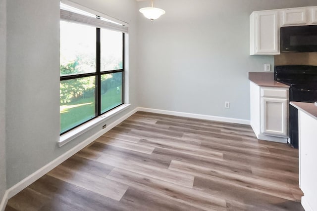 7340 Skillman St Unit 1109, Dallas, TX 75231 - kitchen featuring black appliances, white cabinets, light wood-style flooring, and baseboards