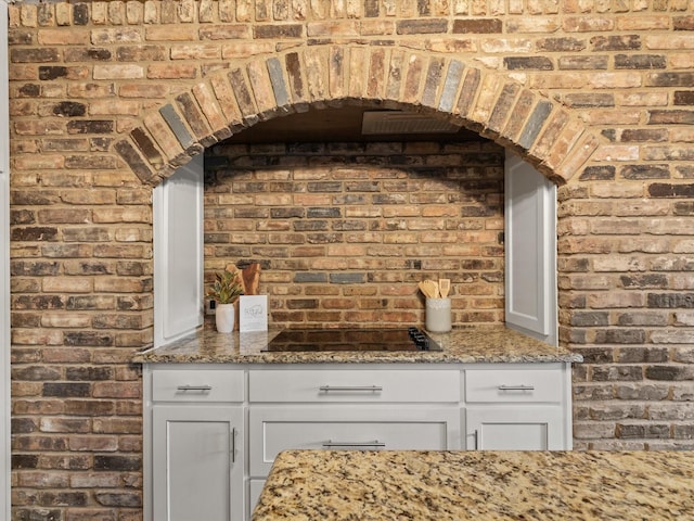 5217 Blue Valley Ct, Fort Worth, TX 76112 - detailed view of black electric cooktop, brick wall, and arched walkways