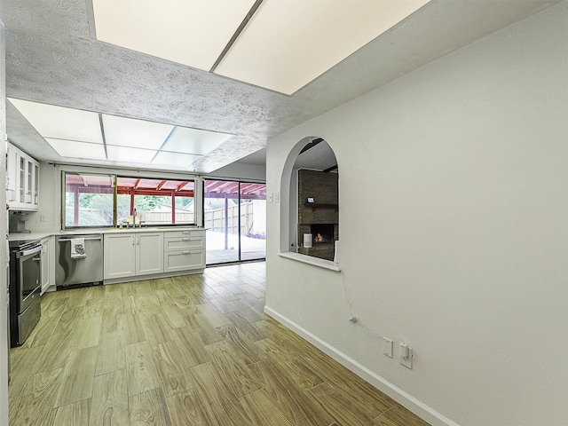 3146 Oak Hill Rd, Carrollton, TX 75007 - kitchen featuring stainless steel appliances, baseboards, light wood finished floors, white cabinetry, and glass insert cabinets