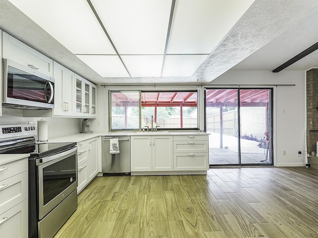 3146 Oak Hill Rd, Carrollton, TX 75007 - kitchen with stainless steel appliances, light wood-style floors, white cabinetry, and light countertops