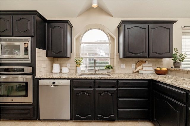 6233 Roaring Springs Dr, North Richland Hills, TX 76180 - kitchen with appliances with stainless steel finishes, a sink, light stone counters, and decorative backsplash