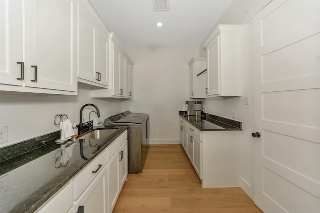 277 Schneider Rd, Sherman, TX 75090 - kitchen featuring a sink, washing machine and clothes dryer, white cabinets, light wood-style flooring, and dark stone countertops