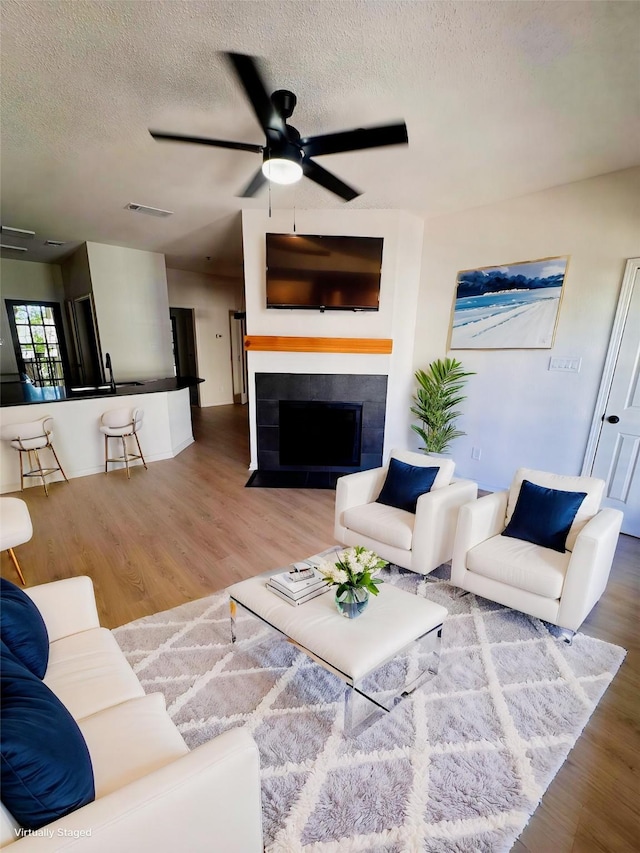 4800 W Lovers Ln Unit 212, Dallas, TX 75209 - living area featuring a textured ceiling, wood finished floors, ceiling fan, and a fireplace with flush hearth