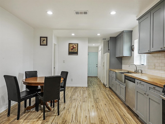 2522 W Jefferson Blvd, Dallas, TX 75211 - kitchen with freestanding refrigerator, stainless steel dishwasher, gray cabinetry, butcher block counters, and light wood-style floors
