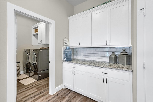 4817 Enclave Dr, Sanger, TX 76266 - kitchen featuring washer and dryer, light wood-type flooring, backsplash, white cabinetry, and light stone countertops