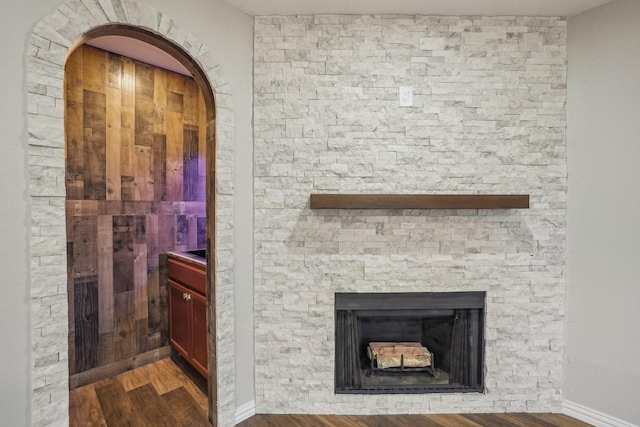 3804 Kathryn Way, Mckinney, TX 75070 - detailed view of wood finished floors, a stone fireplace, arched walkways, and baseboards