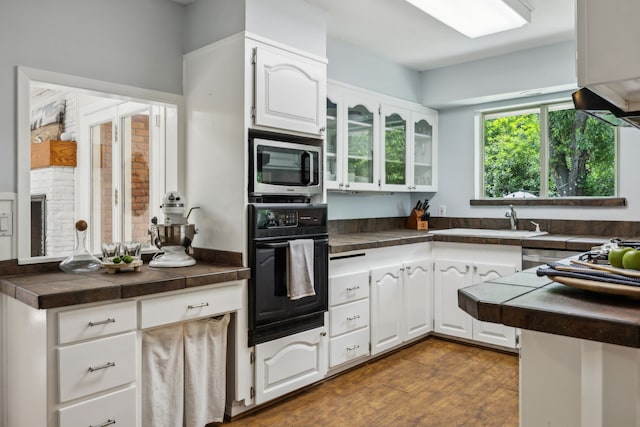 4309 Bilglade Rd, Fort Worth, TX 76109 - kitchen featuring black oven, stainless steel microwave, a sink, white cabinets, and glass insert cabinets