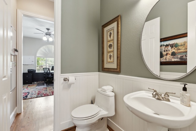 15198 Woodbluff Dr, Frisco, TX 75035 - bathroom featuring a sink, ceiling fan, a wainscoted wall, toilet, and wood finished floors