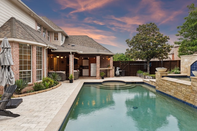 15198 Woodbluff Dr, Frisco, TX 75035 - pool at dusk featuring a patio area, area for grilling, a fenced backyard, and a hot tub