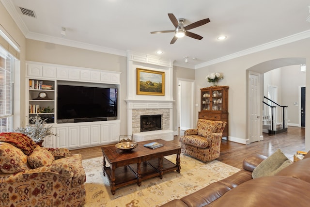 15198 Woodbluff Dr, Frisco, TX 75035 - living area with crown molding, a ceiling fan, arched walkways, wood finished floors, and a fireplace