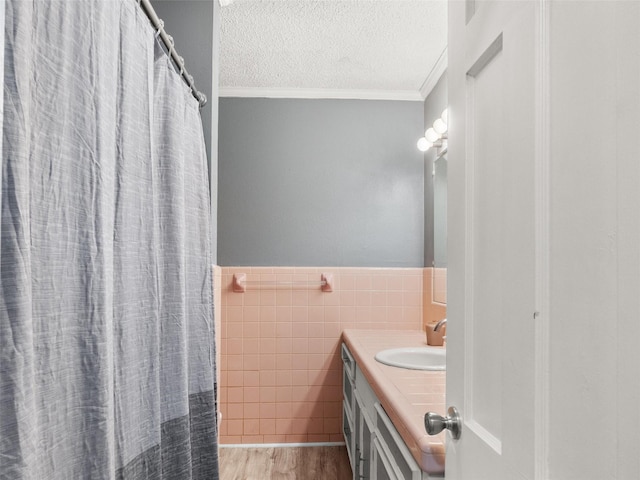 1101 N Bledsoe St, Gilmer, TX 75644 - full bathroom with vanity, tile walls, crown molding, a textured ceiling, and wood finished floors