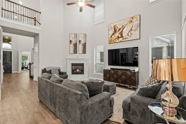 3456 Begonia Ln, Irving, TX 75038 - living area featuring a towering ceiling, a ceiling fan, baseboards, wood finished floors, and a fireplace