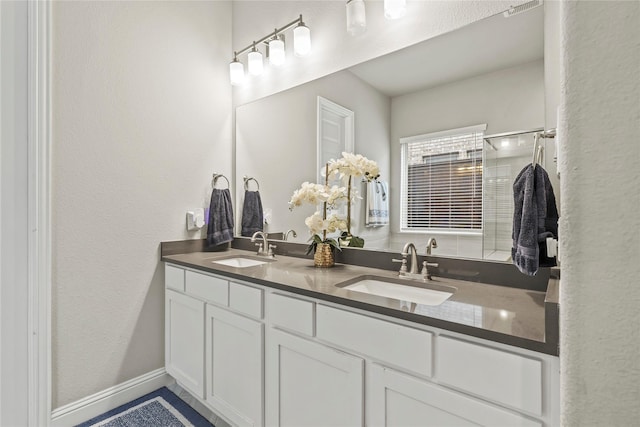 3456 Begonia Ln, Irving, TX 75038 - bathroom featuring double vanity, an enclosed shower, baseboards, and a textured wall