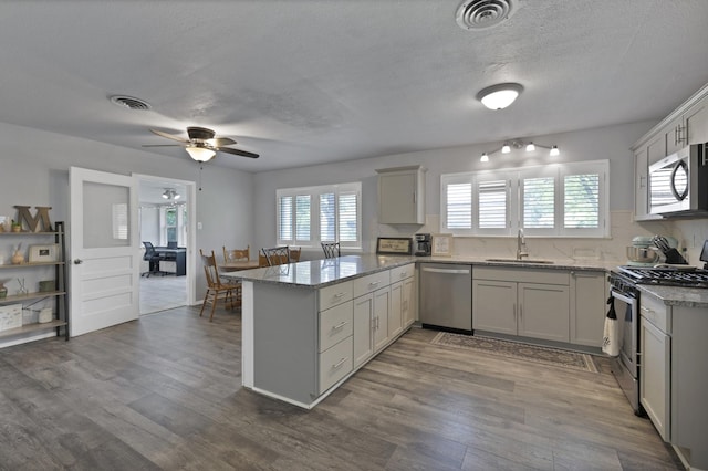 1429 W Water St, Weatherford, TX 76086 - kitchen featuring appliances with stainless steel finishes, a peninsula, a sink, light stone counters, and a ceiling fan