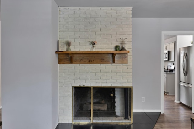 1429 W Water St, Weatherford, TX 76086 - detailed view of stainless steel appliances, a fireplace, dark wood-type flooring, and light countertops