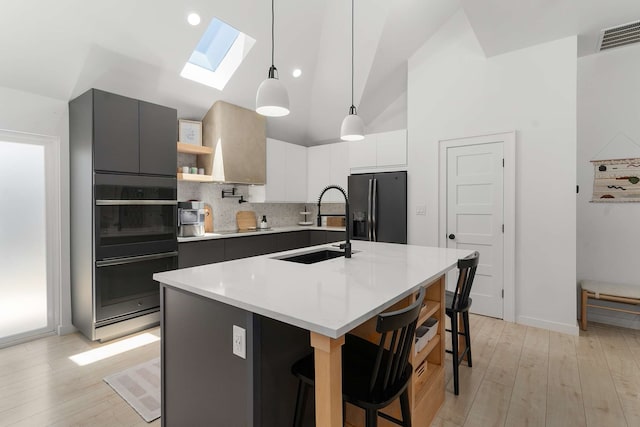 4005 Province Dr, Carrollton, TX 75007 - kitchen with black appliances, a sink, a skylight, decorative backsplash, and light wood-style floors