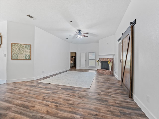 12200 Rolling Ridge Dr, Fort Worth, TX 76028 - unfurnished living room with a ceiling fan, a barn door, wood finished floors, baseboards, and a fireplace