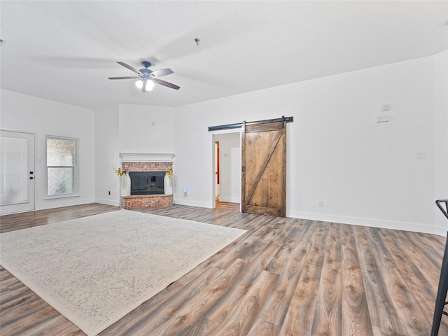 12200 Rolling Ridge Dr, Fort Worth, TX 76028 - unfurnished living room featuring a barn door, a ceiling fan, wood finished floors, baseboards, and a textured ceiling
