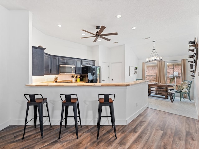 12200 Rolling Ridge Dr, Fort Worth, TX 76028 - kitchen featuring stainless steel microwave, black fridge with ice dispenser, butcher block countertops, recessed lighting, and a kitchen bar