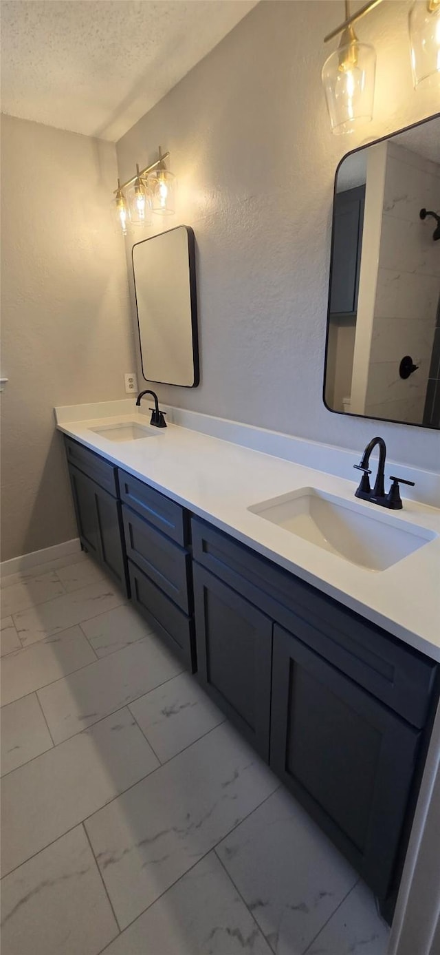 6648 Inwood Dr, Watauga, TX 76148 - bathroom featuring marble finish flooring, a textured ceiling, and double vanity