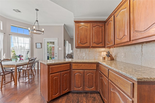 10161 Aragon Dr, Waco, TX 76708 - kitchen with a peninsula, dark wood-style floors, crown molding, a chandelier, and brown cabinetry