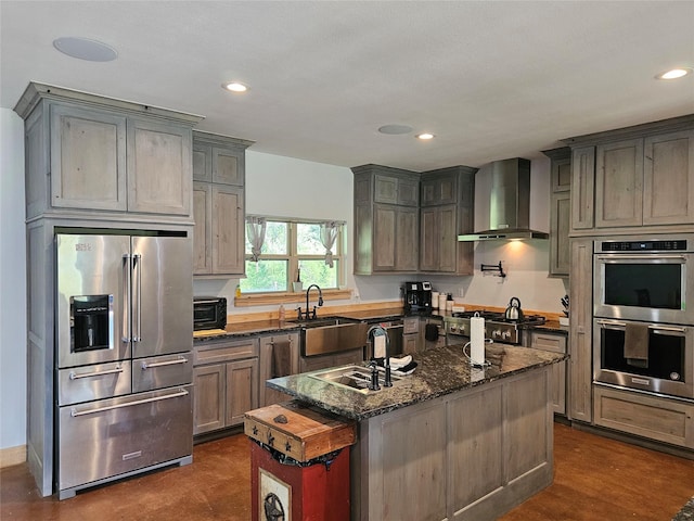 437 County Road 3190, Winnsboro, TX 75494 - kitchen with stainless steel appliances, wall chimney range hood, dark stone countertops, a sink, and recessed lighting