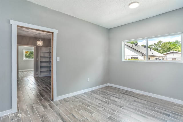 2383 Julia St, Bossier City, LA 71112 - spare room with wood finish floors, baseboards, a textured ceiling, and a chandelier