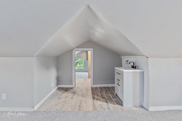 2383 Julia St, Bossier City, LA 71112 - bonus room with a sink, lofted ceiling, light wood-style floors, a textured ceiling, and baseboards