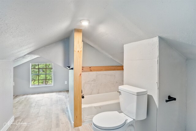 2383 Julia St, Bossier City, LA 71112 - bathroom featuring a textured ceiling, toilet, a bath, lofted ceiling, and wood finished floors