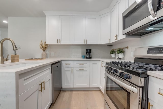 1614 Engle Ave, Dallas, TX 75224 - kitchen with appliances with stainless steel finishes, a sink, white cabinets, a peninsula, and light wood-style floors