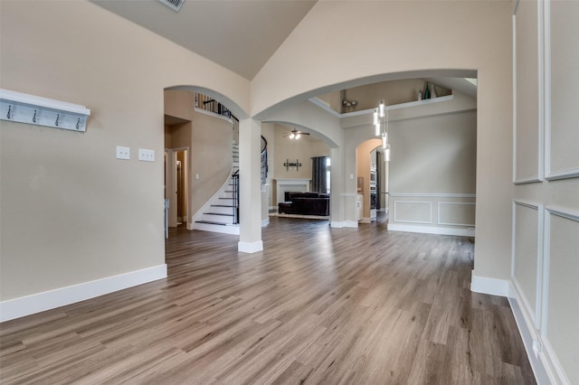 2828 Pino, Grand Prairie, TX 75054 - unfurnished living room with arched walkways, high vaulted ceiling, wood finished floors, a fireplace, and stairs