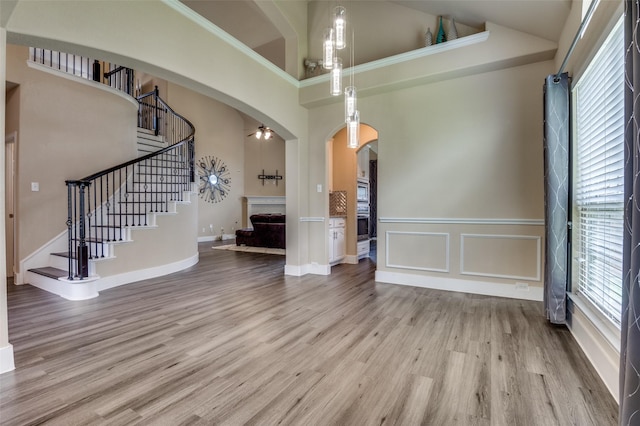 2828 Pino, Grand Prairie, TX 75054 - unfurnished living room featuring arched walkways, a high ceiling, stairway, wood finished floors, and a fireplace