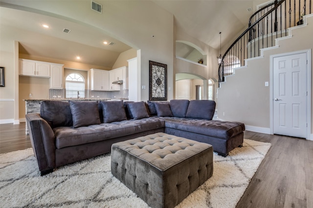 2828 Pino, Grand Prairie, TX 75054 - living room with arched walkways, wood finished floors, high vaulted ceiling, stairs, and recessed lighting