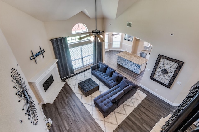 2828 Pino, Grand Prairie, TX 75054 - living area with a fireplace with raised hearth, a towering ceiling, wood finished floors, a ceiling fan, and arched walkways