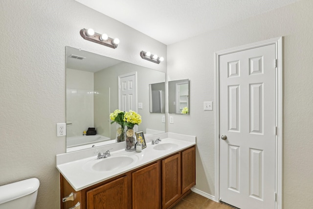 9897 Dartmouth Dr, Frisco, TX 75035 - bathroom featuring double vanity, toilet, tile patterned floors, and a bath
