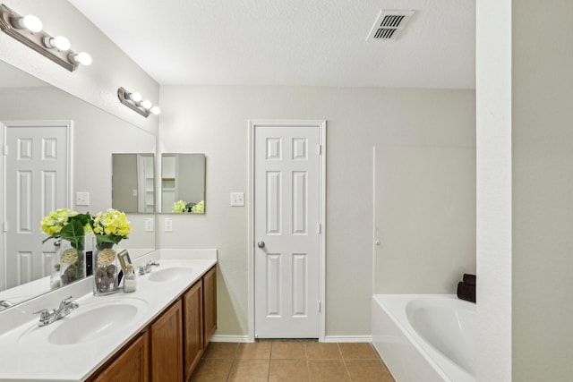 9897 Dartmouth Dr, Frisco, TX 75035 - full bathroom with tile patterned floors, a bath, double vanity, baseboards, and a textured ceiling
