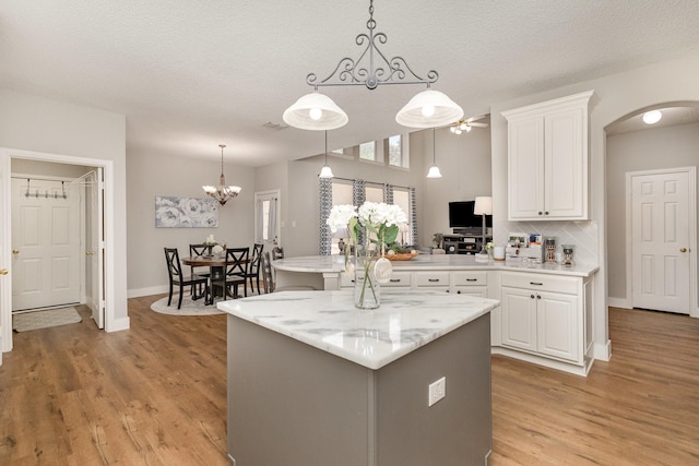 1304 Waterdown Dr, Allen, TX 75013 - kitchen with light wood-style flooring, white cabinets, arched walkways, decorative light fixtures, and a textured ceiling