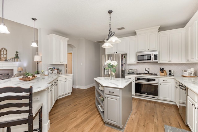 1304 Waterdown Dr, Allen, TX 75013 - kitchen with stainless steel appliances, arched walkways, backsplash, gray cabinetry, and white cabinetry