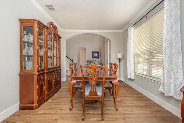1304 Waterdown Dr, Allen, TX 75013 - dining room featuring arched walkways, baseboards, crown molding, light wood-style floors, and a textured ceiling