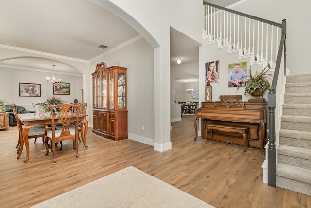 1304 Waterdown Dr, Allen, TX 75013 - dining space with arched walkways, crown molding, stairs, light wood-style floors, and a chandelier