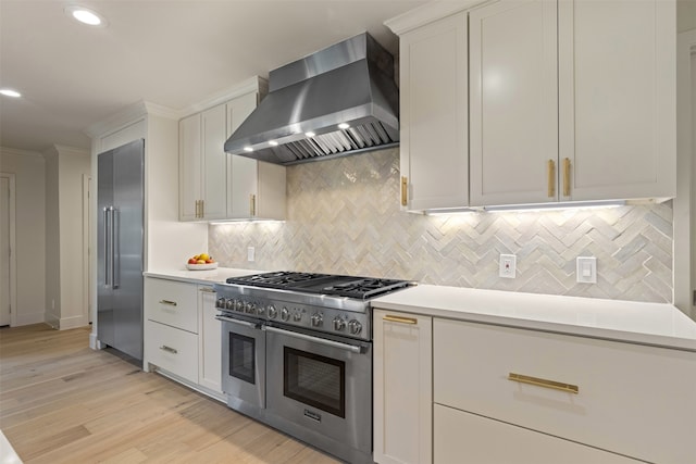 4016 Goodfellow Dr, Dallas, TX 75229 - kitchen featuring high quality appliances, wall chimney range hood, light countertops, light wood finished floors, and white cabinets