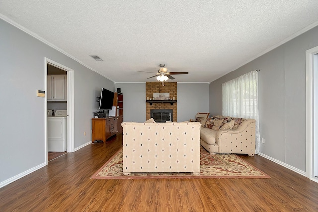3929 Wrenwood Dr, Fort Worth, TX 76137 - living room featuring washer / dryer, ceiling fan, dark wood-style flooring, crown molding, and a fireplace