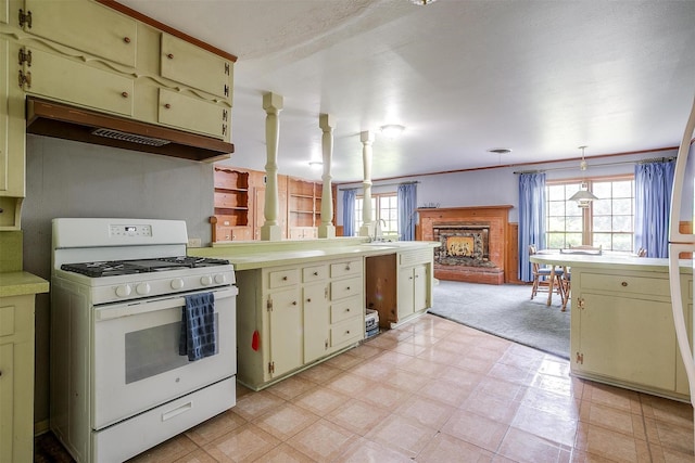 4524 Morris Ct, Fort Worth, TX 76103 - kitchen with white gas range, under cabinet range hood, light countertops, and cream cabinetry