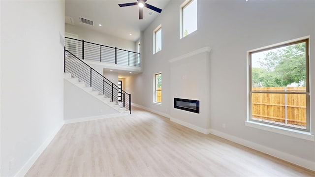6860 Zuefeldt Dr, Arlington, TX 76002 - unfurnished living room with a towering ceiling, wood finished floors, baseboards, stairway, and a ceiling fan