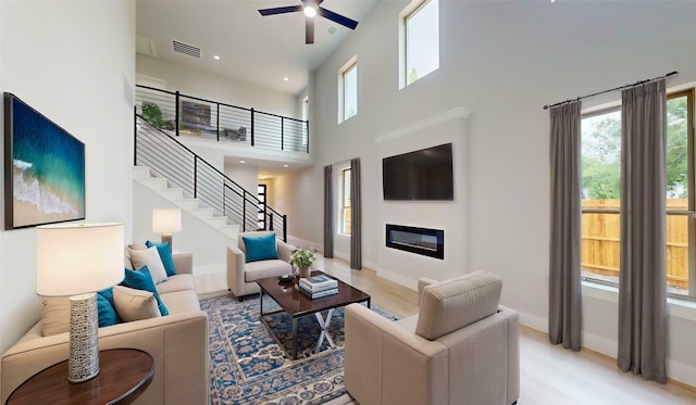 6860 Zuefeldt Dr, Arlington, TX 76002 - living area featuring stairs, ceiling fan, a towering ceiling, light wood-style floors, and baseboards