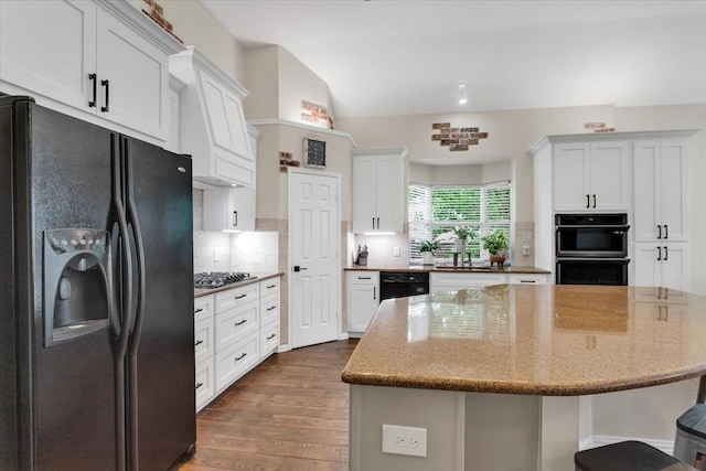 11538 Corsicana Dr, Frisco, TX 75035 - kitchen featuring black appliances, a kitchen island, dark wood finished floors, tasteful backsplash, and light stone countertops