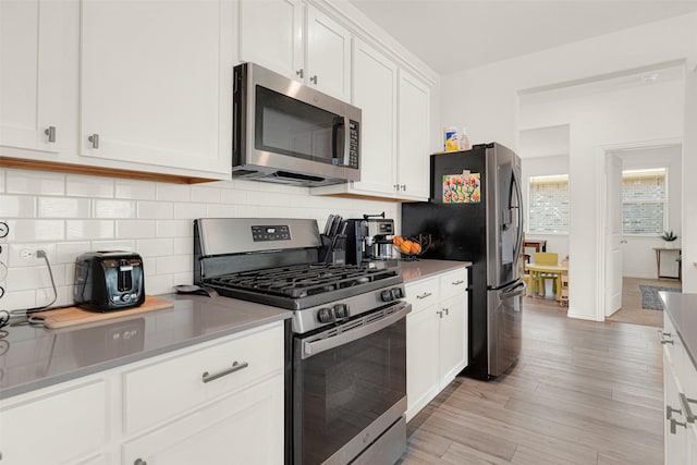 511 Poplar St, Princeton, TX 75407 - kitchen featuring appliances with stainless steel finishes, tasteful backsplash, white cabinetry, light wood-type flooring, and baseboards