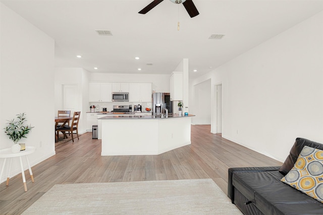 511 Poplar St, Princeton, TX 75407 - kitchen featuring stainless steel appliances, open floor plan, light wood-style flooring, ceiling fan, and white cabinets